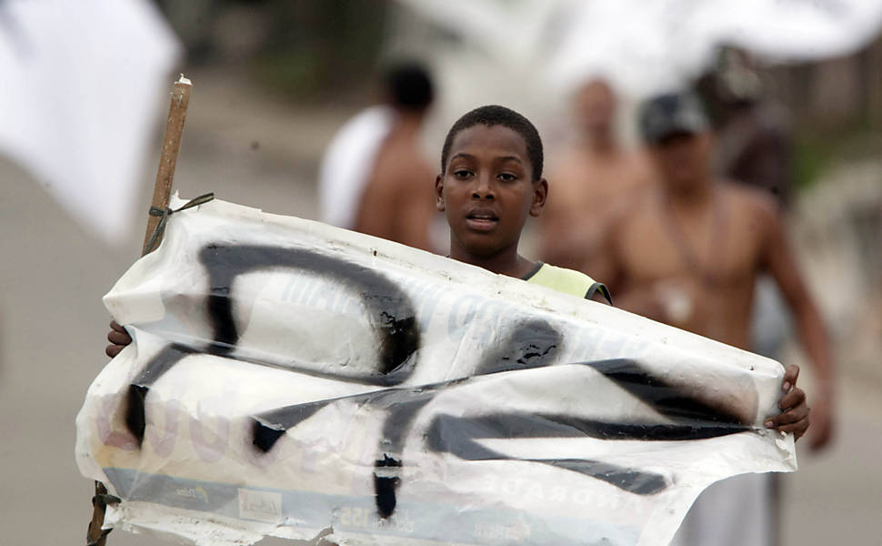 Morador do Complexo do Alemão, conjunto de favelas na zona norte do Rio, exibe cartaz pedindo paz <b>
