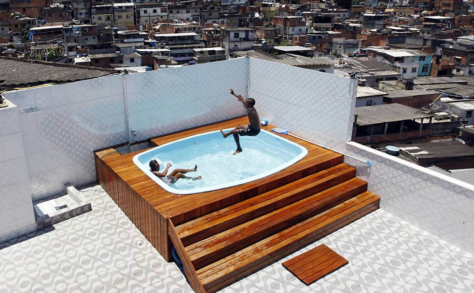 Crianças brincam em piscina construída na casa de um dos chefes do tráfico de drogas do Complexo do Alemão, na zona norte do Rio <b>