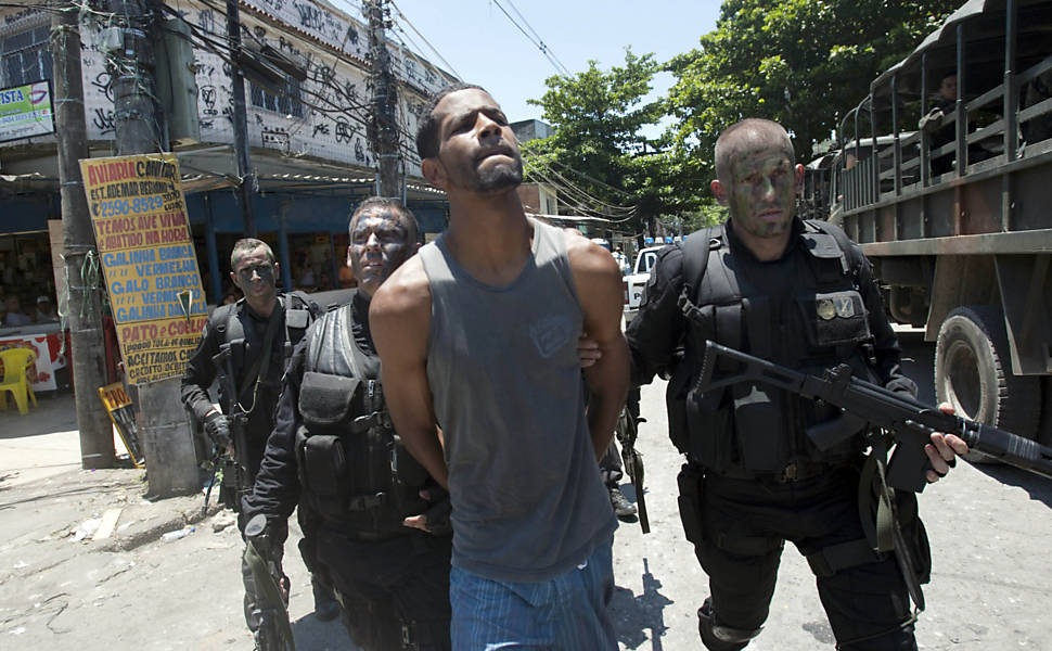 Traficante conhecido como Vassoura, acusado de gerenciar o tráfico na favela da Fazendinha, é preso e levado por policiais durante operação de ocupação do Complexo do Alemão, na zona norte do Rio <b>