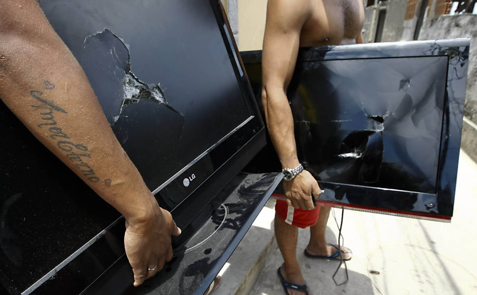 Moradores do Complexo do Alemão, na zona norte do Rio, mostram TVs que, segundo eles, foram quebradas por policias durante revista em suas casas após a ocupação do conjunto de favelas <b>