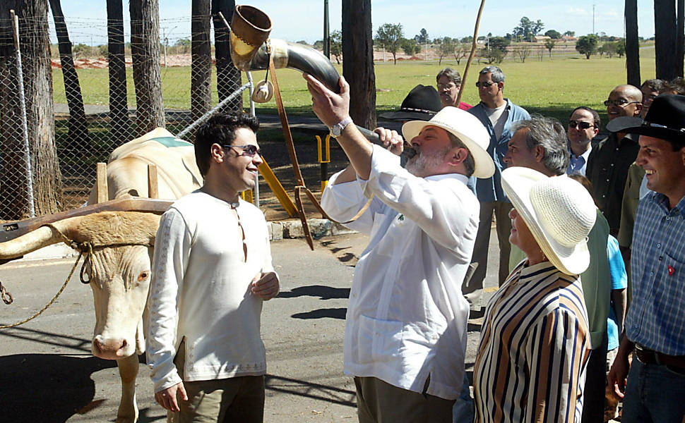 Na Granja do Torto, o presidente Luiz Inácio Lula da Silva toca berrante ao lado de sua mulher, Marisa Letícia Lula da Silva, e do cantor Zezé Di Camargo, em Brasília (DF); à noite, Lula recebeu convidados para o arraial em homenagem aos seus 30 anos de casamento