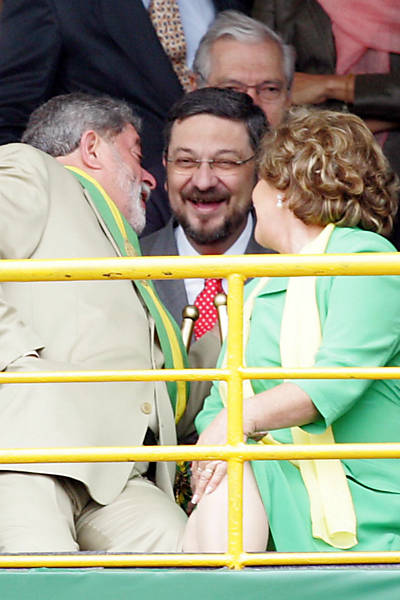 O presidente Luiz Inácio Lula da Silva (à esq.) conversa com o ministro da Fazenda, Antonio Palocci Filho, e com a primeira-dama, Marisa Letícia Lula da Silva, durante as festividades do desfile de 7 de setembro, em Brasília (DF). Durante seu discurso em cadeia de rádio e TV, o presidente disse que não admitirá "qualquer contemporização, qualquer acordo subalterno" para evitar punições aos políticos envolvidos em casos de corrupção, referindo-se à crise do "Mensalão"