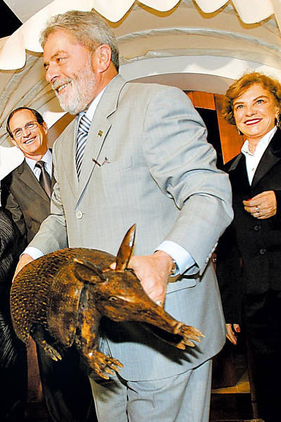 O presidente Luiz Inácio Lula da Silva segura uma estátua de um tatu ao chegar à casa do ministro do Desenvolvimento, Luiz Fernando Furlan para um jantar com empresários dos setores de siderurgia, mineração, automotivo e de papel e celulose