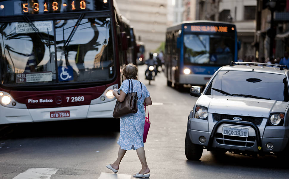 Pedestre atravessa rua do centro de São Paulo em meio a carros, motos e ônibus; centro lidera o ranking de atropelados <b>