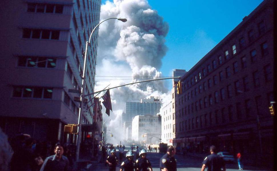 População tenta fugir da onda de poeira formada pelo desabamento das torres gêmeas do World Trade Center <b>