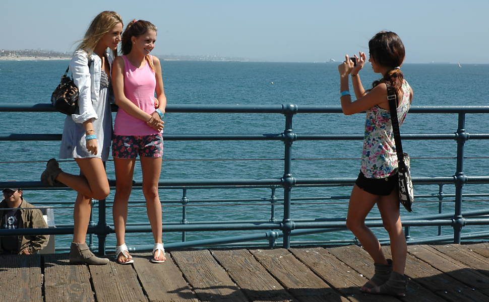 Garotas tiram fotos no píer Santa Mônica 
