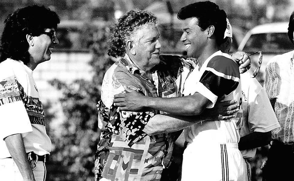 O jogador Muller abraça o cantor Tinoco, observado pelo filho Tinoquinho, à esquerda, antes do treino do São Paulo 