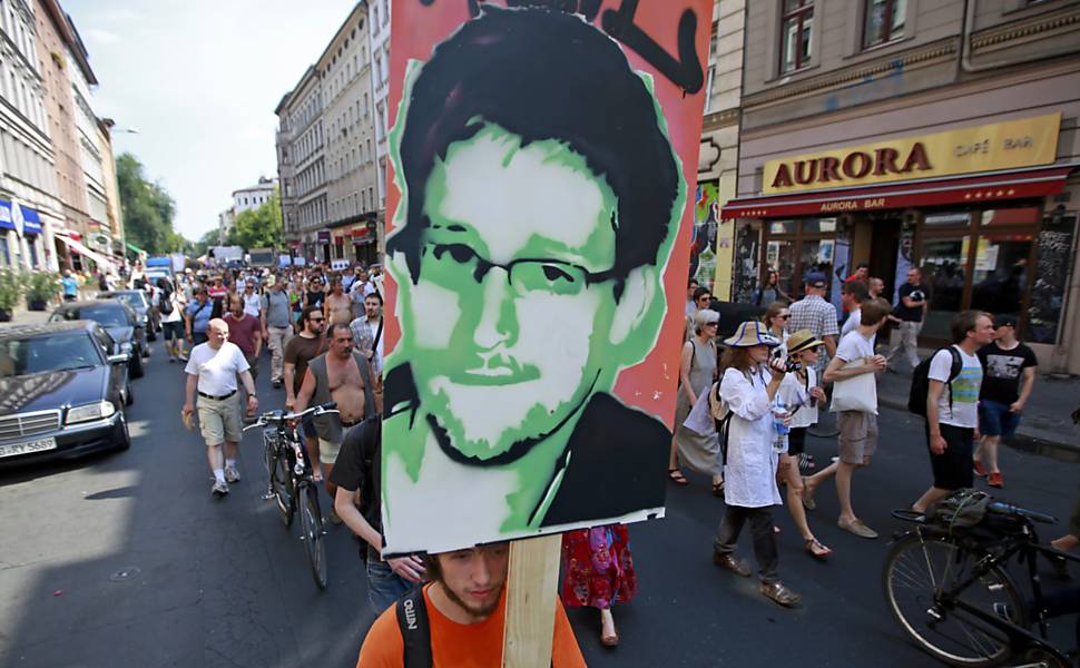 Manifestantes empunham cartaz com o rosto do delator Edward Snowden durante protesto em Berlim