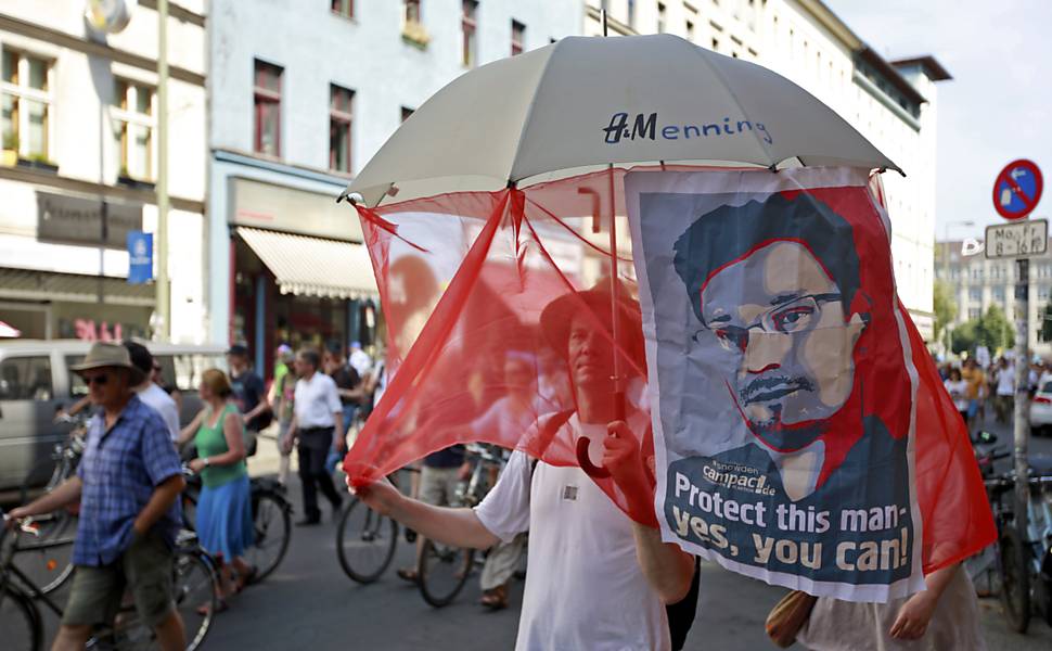 Manifestantes empunham cartaz com o rosto do delator Edward Snowden durante protesto em Berlim