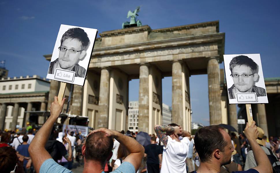 Manifestantes empunham cartaz com o rosto do delator Edward Snowden durante protesto em Berlim