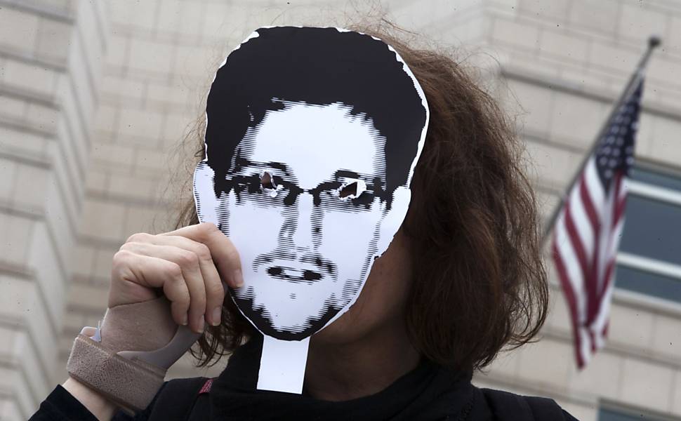 Mulher segura máscara com o rosto de Edward Snowden em protesto em Berlim