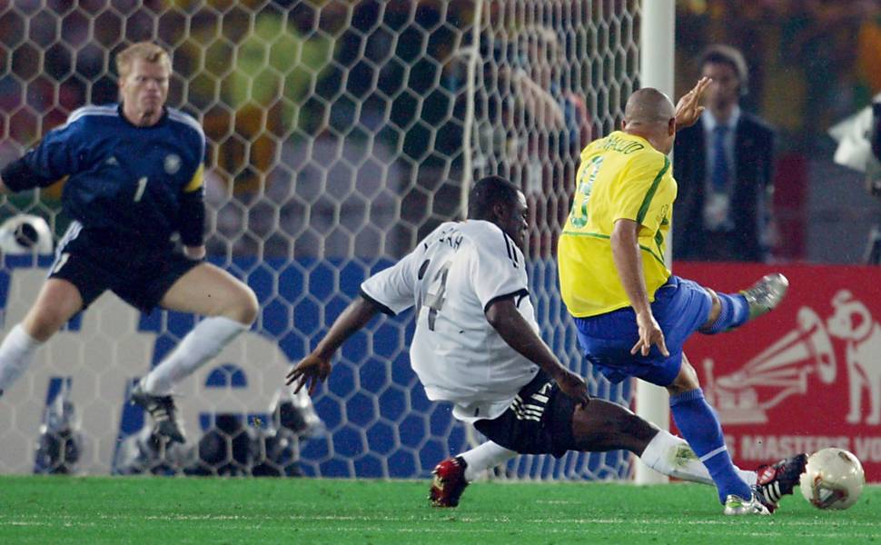 Ronaldo se antecipa a Asamoah e bate de direita, com precisão, fazendo 2 a 0 para o Brasil contra a Alemanha. Fenômeno marcou os dois gols brasileiros da decisão e, com oito no torneio, terminou o Mundial como artilheiro