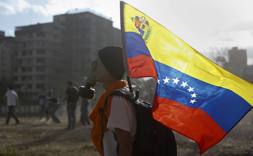 Manifestante carrega a bandeira venezuelana durante protestos na praça Altamira, em Caracas  