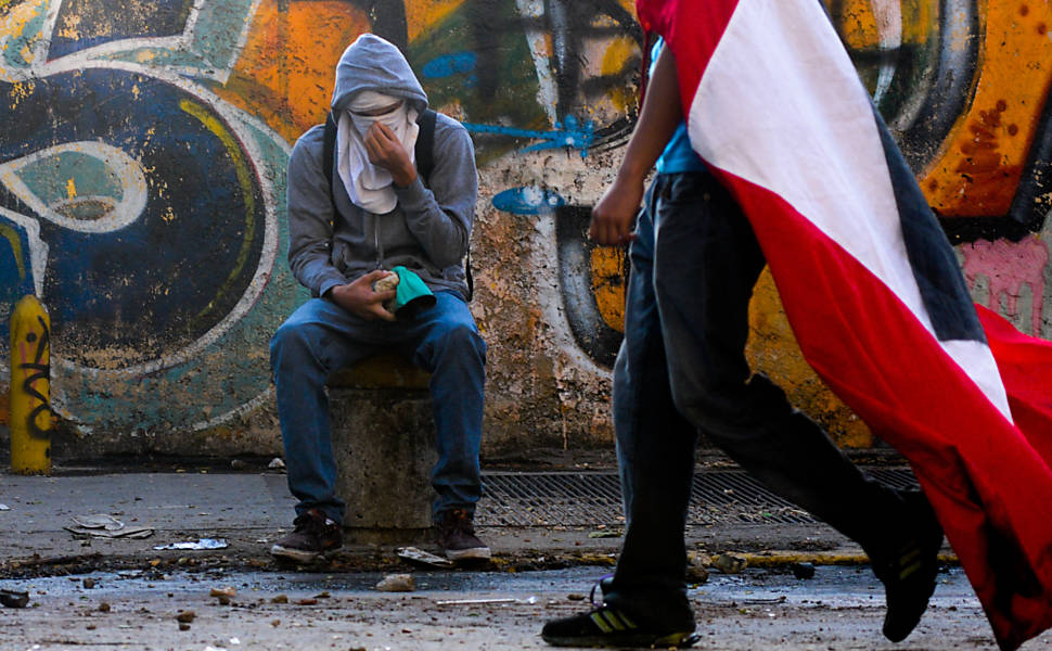 Manifestante recupera o fôlego durante protestos antigoverno em Chacao 
