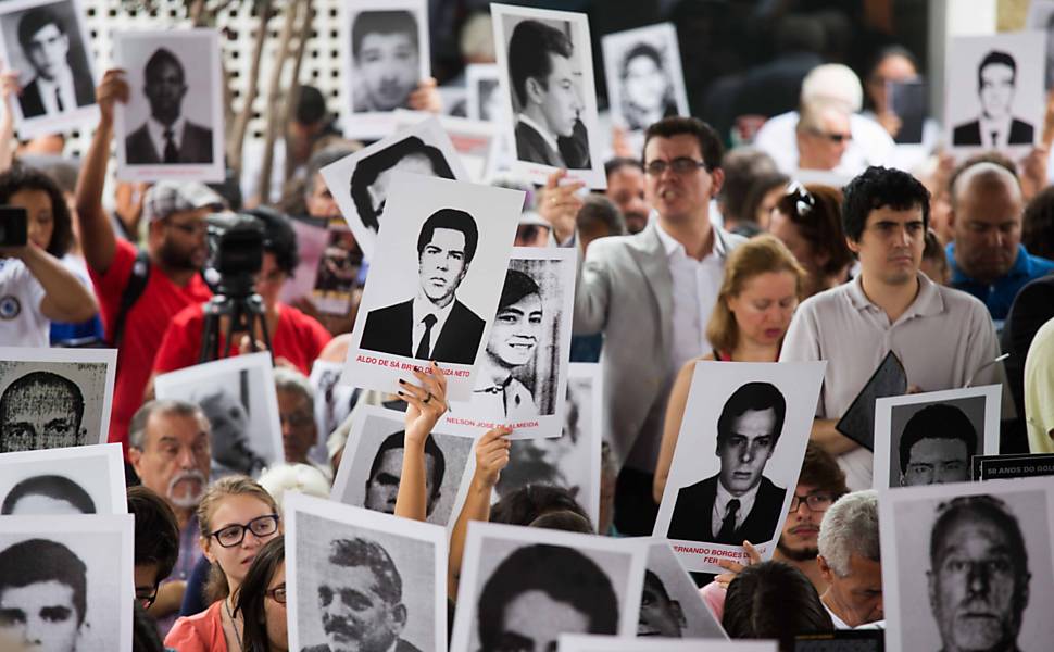 Manifestantes seguram cartazes com imagens de vítimas da ditadura