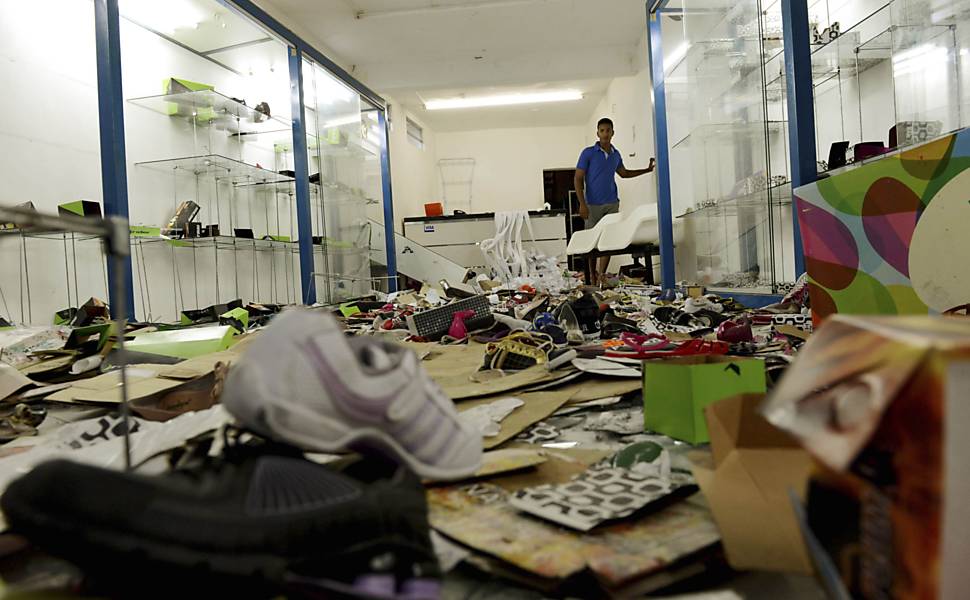 Homem observa loja que foi saqueada durante a greve da polícia em Salvador, Bahia