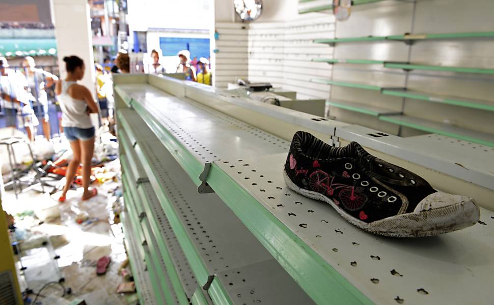 Mulher observa loja que foi saqueada durante a greve da polícia em Salvador, Bahia