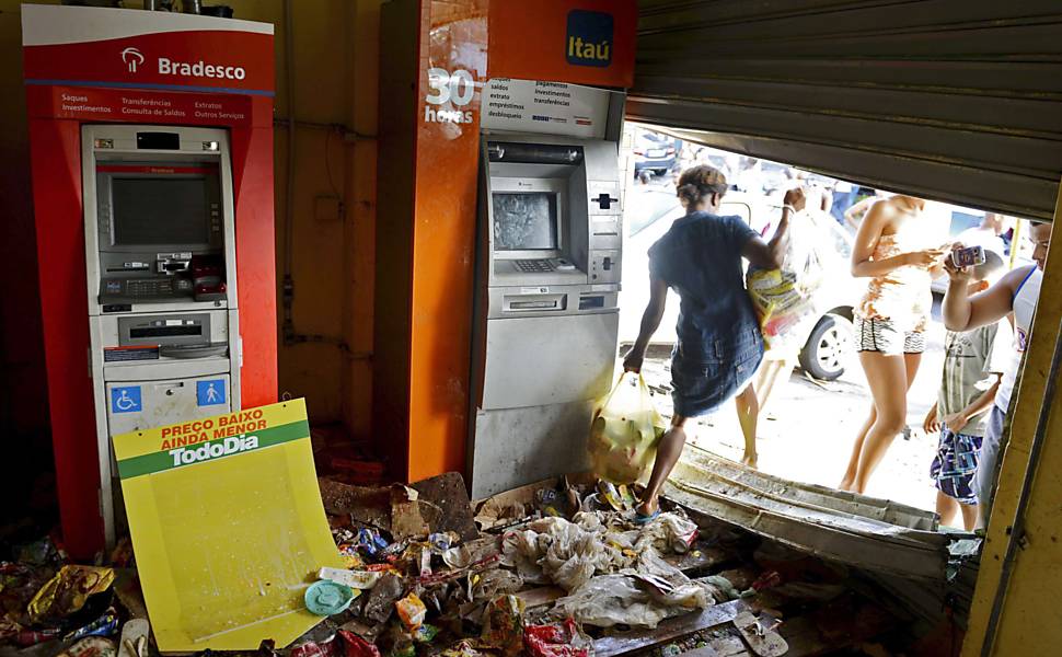 Mulher carrega sacos com mercadorias de um supermercado que foi saqueado durante a greve da polícia em Salvador, na Bahia