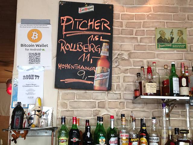 Cartazes fazendo propaganda do bitcoin no Room77 