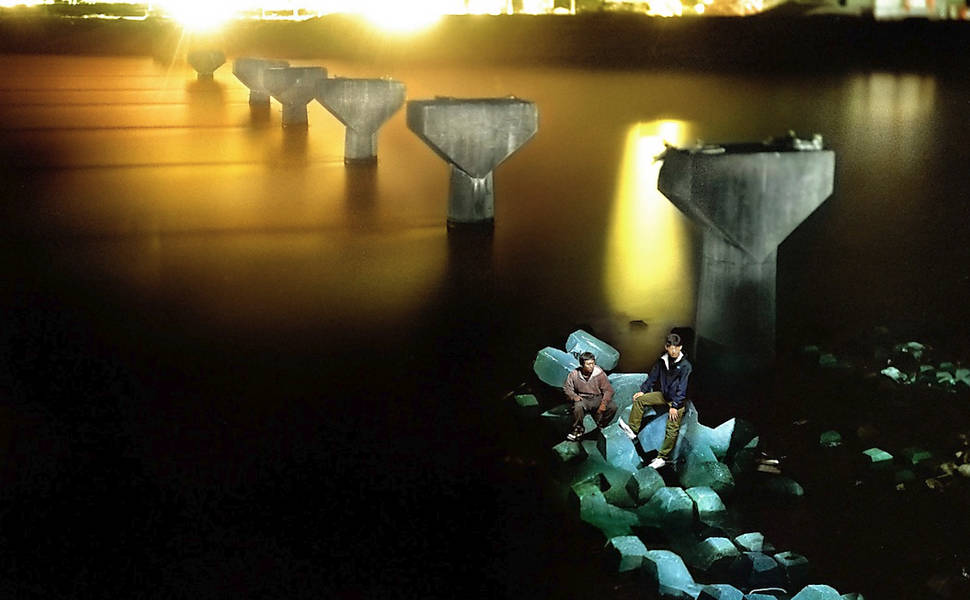 Dois homens sentam ao lado dos pilares da ponte ferroviária de Otsuchi, destruída pelo tsunami que atingiu a região em 2015