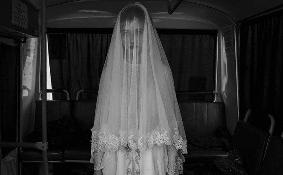 Nesta imagem, Rada, de 14 anos, experimenta o vestido de casamento desenhado por sua irmã em um ônibus durante o ensaio para um filme. A mostra "Spasibo", de fotografias de Monteleone, fica até 3 de novembro na Galeria Saatchi, em Londres