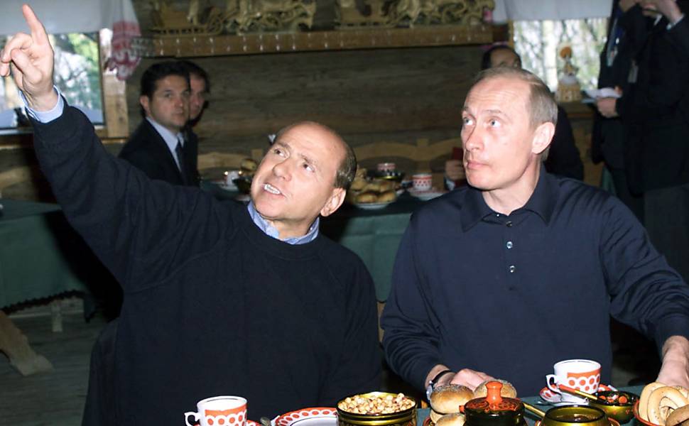Vladimir Putin, presidente russo, e Silvio Berlusconi, então primeiro-ministro italiano, experimentam refeição tradicional russa em resort de Sochi, em abril de 2002