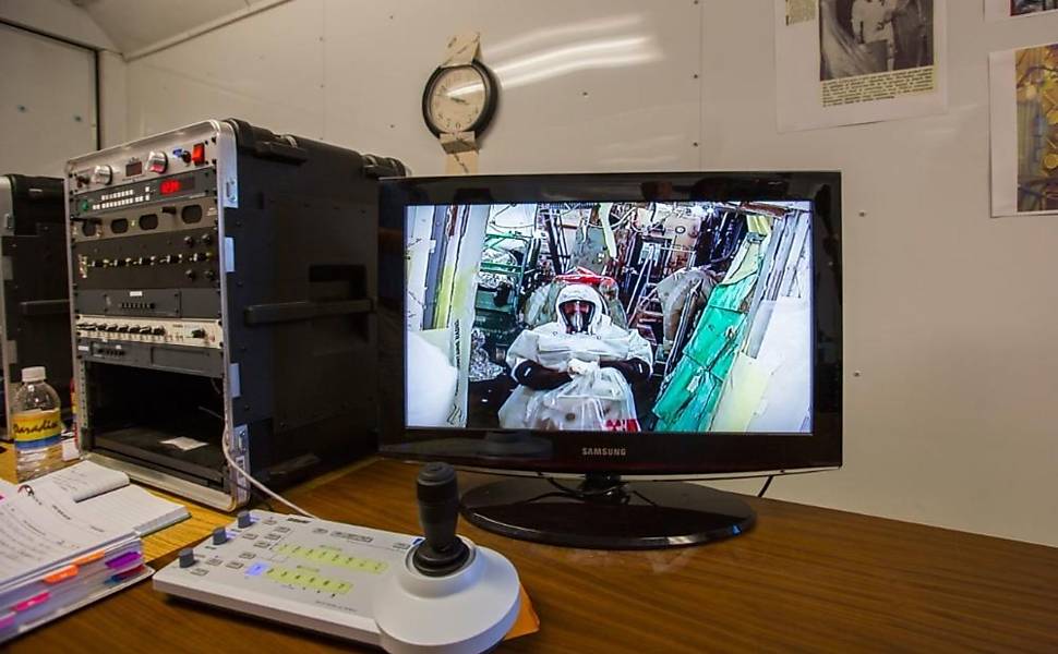 Um funcionário de Hanford, visto por um monitor num traje de proteção nível B, limpando a sala mais perigosa de Hanford Site, a Instalação de Recuperação de Amerício, também conhecida como “Sala McCluskey”. A sala foi batizada em homenagem a Harold McCluskey, que ficou ferido em 1976 depois que uma explosão expôs Harold e a sala a material radioativo