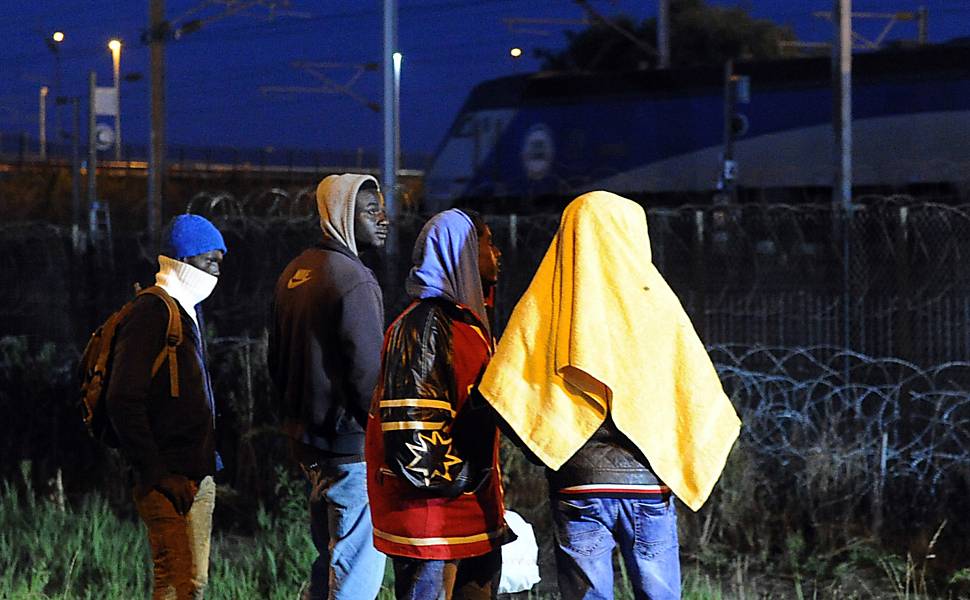  
Imigrantes em frente a cercas na cidade de Calais, França, onde muitos tentam usar o túnel do Canal da Mancha para chegar ao Reino Unido
