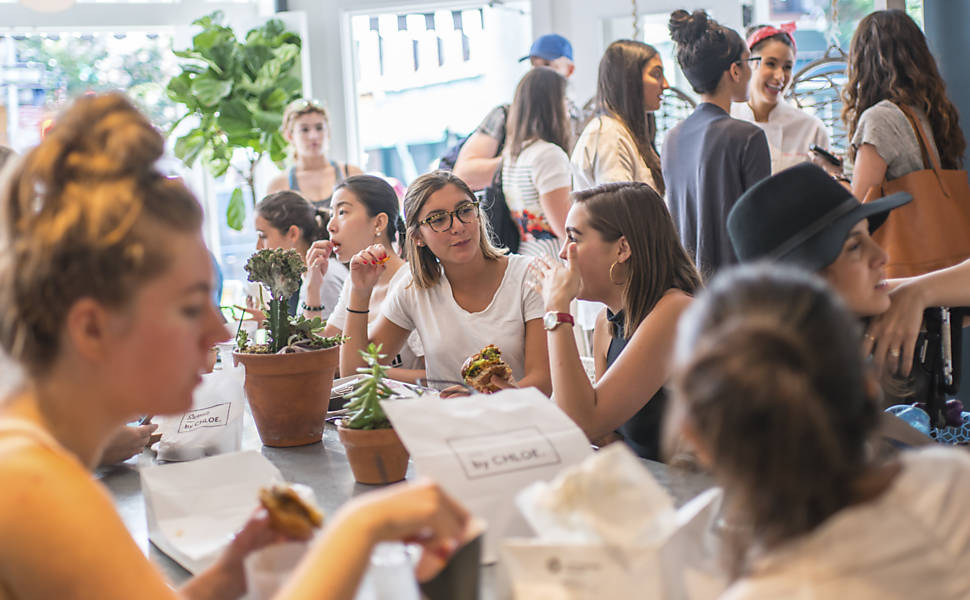 Clientes no By Chloe em Nova York. A chef Chloe Coscarelli, autora de diversos livros de culinária, enfatiza que seus hambúrgueres vegetarianos e saladas com tacos não deixa os fregueses famintos, mastigando as próprias juntas