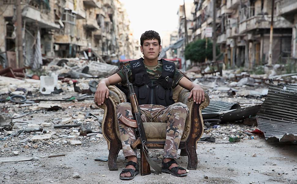 "Nadir", Aleppo, Síria, junho de 2014 <p>
Jovem combatente sentado em uma poltrona em meio a rua totalmente devastada pelo combate entre o Exercito de Libertação da Síria e as forças de Bashar Al-Assad. Salahideen