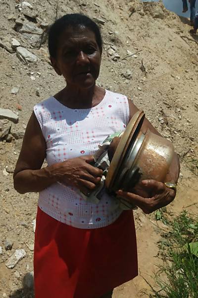 A ex-moradora de Bento Rodrigues Maria Gomes recupera algumas panelas em meio ao que restou de sua casa, em Mariana