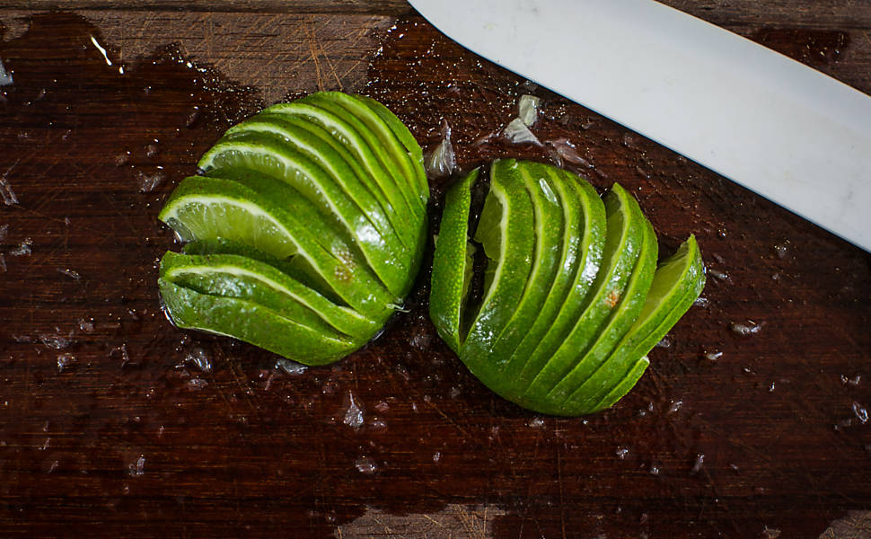 Fatie finamente as metades, sem desprende-las. Em um copo de caipirinha, adicione o limão e 2 col. (sopa) do xarope de açúcar