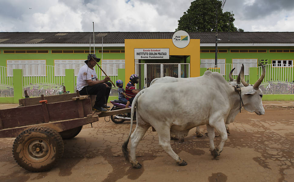 Carro de boi passa em frente à escola Instituto Odilon Pratagi, em Brasiléia