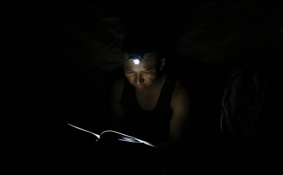 Soldado rebelde das Farc usa uma lanterna de cabeça para ler em acampamento nas selvas do sul de Putumayo, na Colômbia. Ele lê uma copia do diário da correspondência do falecido líder guerrilheiro Manuel Marulanda Velez