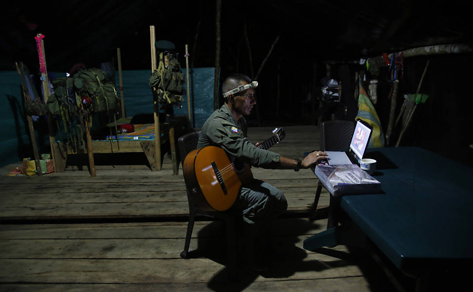 Manuel, comandante de nível médio de uma das frentes das Farc, estuda violão através da internet em um acampamento no sul do Putumayo, Colômbia. O acampamento oferece acesso regular à internet para os comandantes