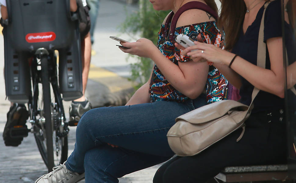 Pedestres usam o celular
