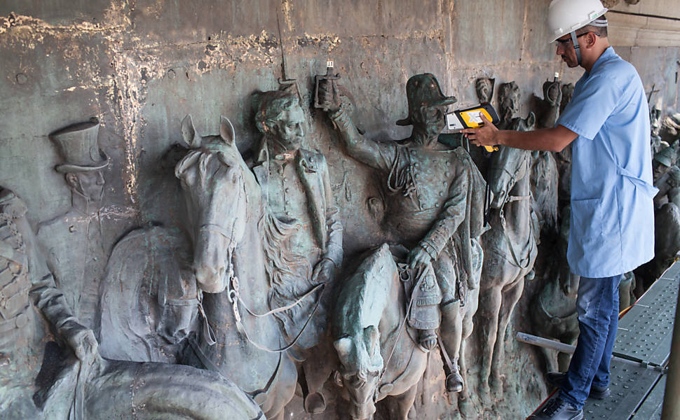 Equipe do Senai utiliza aparelho usado para analisar ligas metálicas utilizadas na feitura do painel de bronze do  monumento 