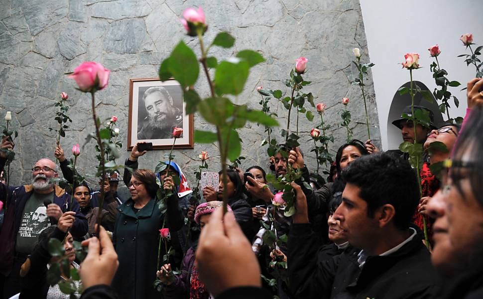 Pessoas seguram flores em homenagem a Fidel Castro, que morreu na última sexta feira aos 90 anos, na embaixada de Cuba em Bogotá, Colômbia