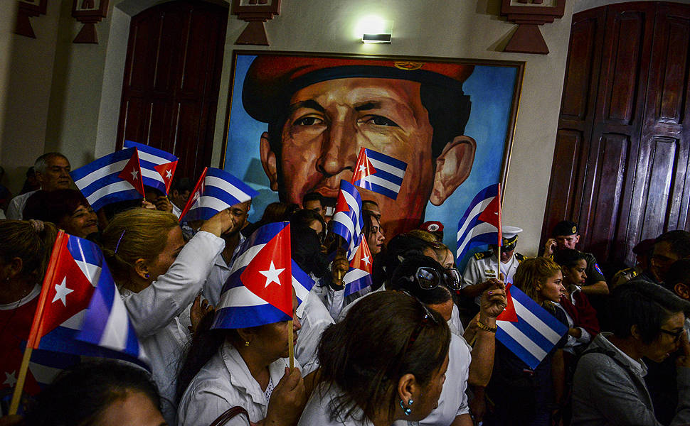 Apoiadores do presidente venezuelano Nicolas Maduro acenam com bandeiras de Cuba em frente a imagem de Hugo Chavez, durante cerimônia de homenagem a Fidel Castro em Caracas