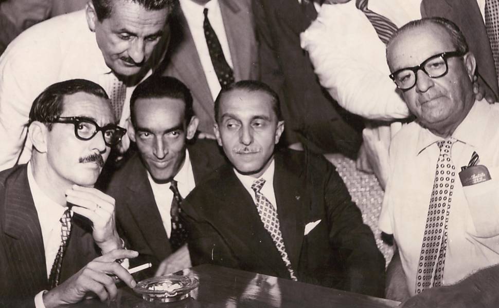 Jânio (à esq.) em companhia de Carvalho Pinto, momentos antes de seu embarque, em Santos (SP). Centenas de pessoas, com faixas ("Jânio com quem quiser, mas sempre Jânio") e foguetes, aguardavam no cais do porto a chegada do ex-governador paulista