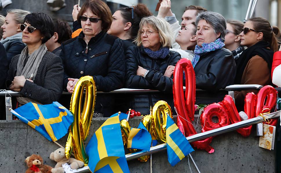 Pessoas assistem a uma cerimônia na praça Sergels Torg, em Estocolmo, perto do ponto onde um caminhão entrou em uma loja de departamento na sexta-feira (7)