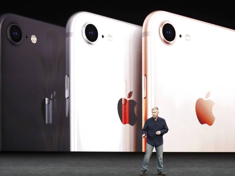 Retrato de uma apresentação do iPhone 8; um homem gesticula, atrás está uma telão com três iphones