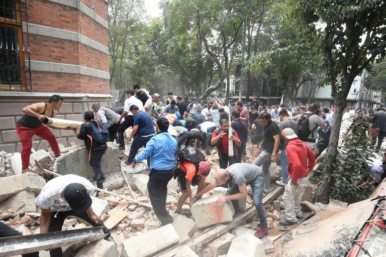 People remove debris of a damaged building after a real quake rattled Mexico City on September 19, 2017 while an earthquake drill was being held in the capital. A powerful earthquake shook Mexico City on Tuesday, causing panic among the megalopolis' 20 million inhabitants on the 32nd anniversary of a devastating 1985 quake. The US Geological Survey put the quake's magnitude at 7.1 while Mexico's Seismological Institute said it measured 6.8 on its scale. The institute said the quake's epicenter was seven kilometers west of Chiautla de Tapia, in the neighboring state of Puebla. / AFP PHOTO / Alfredo ESTRELLA