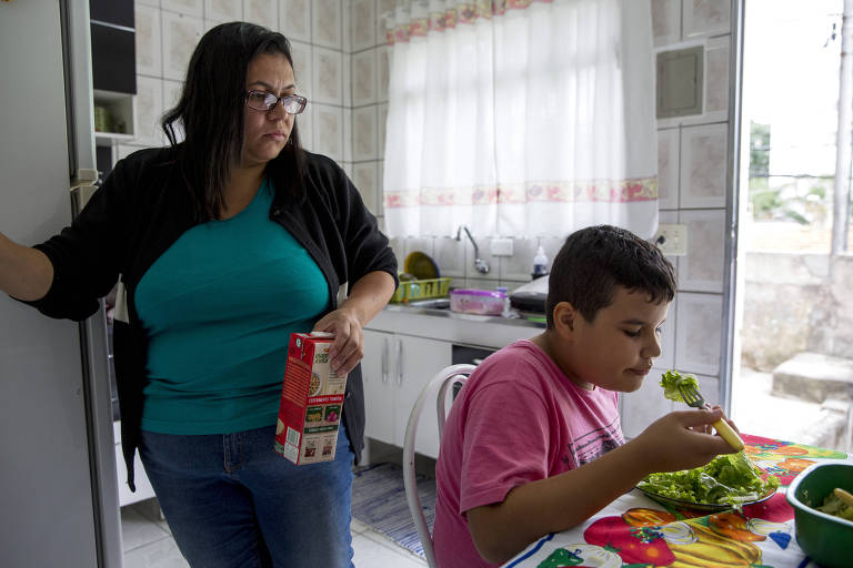 Em São Paulo, Isaac, 9, come salada enquanto sua mãe, Elaine Pereira dos Santos, observa. Ela ficou contente quando, ainda pequeno, não muito depois de provar seu primeiro lanche no McDonald's, o garoto começou a ganhar peso. Agora Isaac já precisa usar roupas para adolescentes e pesa mais de 60 quilos