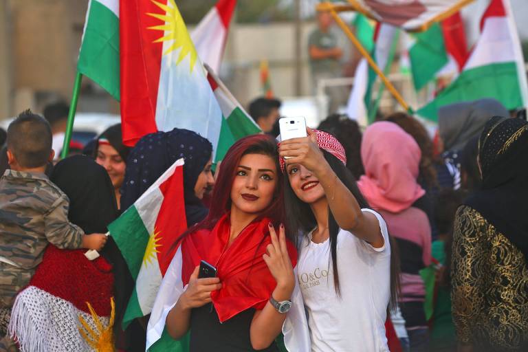 A Syrian Kurdish girl flashes the victory gesture as she poses for a "selfie" photograph with another girl, while celebrating in the northeastern Syrian city of Qamishli on September 25, 2017, in support of the independence referendum in Iraq's autonomous northern Kurdish region. Iraqi Kurds voted in an independence referendum, defying warnings from Baghdad and their neighbours in a historic step towards a national dream. / AFP PHOTO / Delil souleiman