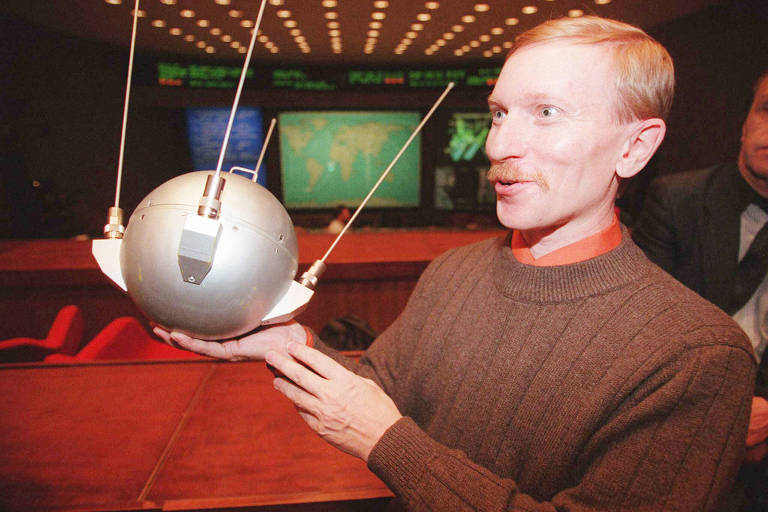 Sergei Samburov, funcionário do Centro de Controle de Missões Espaciais da Rússia, segura maquete de um dos primeiros satélites do mundo
