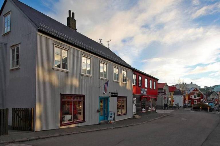 A imagem mostra uma rua em uma cidade na Islndia. As casas  beira da pista so de arquitetura tpica islandesa, que so sobrados feitos de madeira com telhados ngremes.