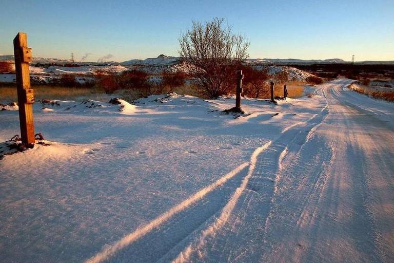 A foto mostra uma grande plancie coberta de neve.  direita,  possvel ver um caminho formado pelos pneus dos carros que passam por ali. Bem ao fundo, na linha do horizonte, est uma cadeia de montanhas