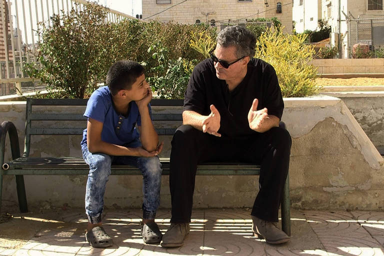 O cineasta Amos Gitai conversa com menino palestino em cena de 'A Oeste do Jordo