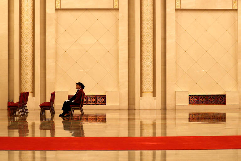 Membro da equipe de logística do Congresso do Partido Comunista senta-se em um dos corredores do Grande Salão do Povo